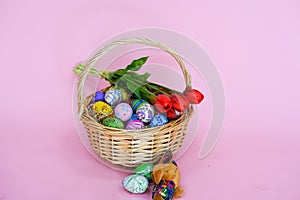 THe painted colorful Easter egg in the basket on the pink background copyspace