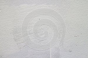 Painted concrete wall in white with vertical crack lines and rough surface visible.