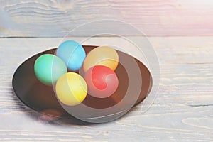Painted easter eggs on black plate on wooden background