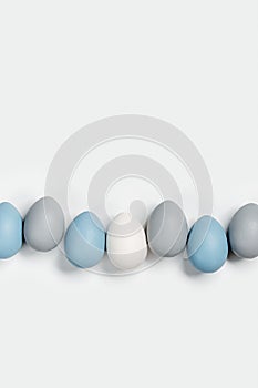 Painted Easter eggs blue, gray colored in row on white background with copy space. Chicken egg natural pastel shades