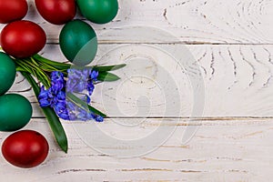 Painted Easter eggs and blue scilla flowers on white wooden background. Easter composition. Top view, copy space