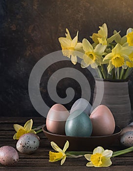 Painted Easter eggs with daffodil flowers on dark rustic background
