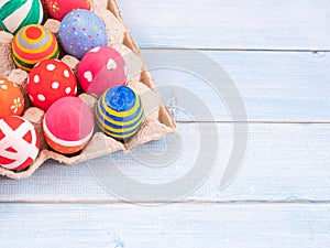 Painted easter eggs in the egg tray on blue wood plank background photo