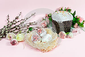 Painted Easter eggs near cupcake and willow branches are decorated with natural fresh flower heads