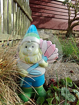 Painted garden gnome  with white picket fence and red sided house