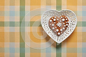 Painted gingerbread cookie in the shape of a heart on a plate in the shape of a heart