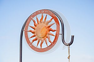 Painted golden, metal sun burst, surrounded by red, flat medal circle attached to a bird feeder rod