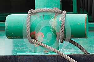 Painted green cross-shaped bollard and tied hawser photo