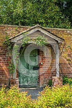 Painted green door and porch in walled garden wall