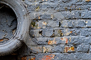 Painted in grey tyre lies on the gray brick wall