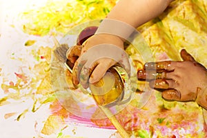 Painted hands smudging colors on messy table