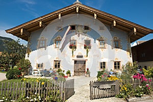 Painted house in St. Johann, Austria. Traditional house with wooden windows and lots of flwers in front garden.