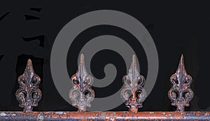Painted iron gate finials in a row on black background
