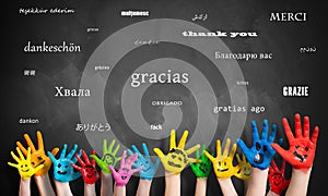 Painted kids hands in front of a blackboard with the message `thank you` in many languages