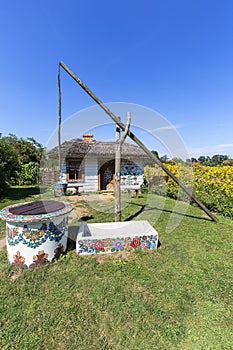 Painted old wooden cottage, well and pail, decorated with a hand painted flowers, Zalipie, Poland