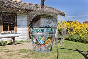 Painted old wooden cottage, well and pail, decorated with a handmade painted flowers, Zalipie, Poland