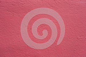 Painted plastered wall of pink color. Abstract background with fine concrete texture painted in pink color.