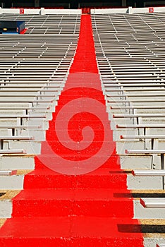 A painted red aisle travels up past the bleachers of a football stadium