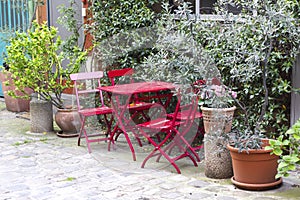 Painted in red garden furniture in the intimate cobblestone courtyard in Paris