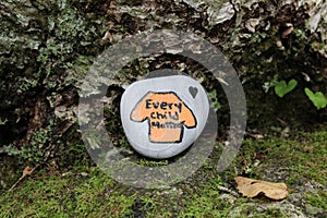 A painted rock at the base of a tree along a trail in Nova Scotia orange shirt every child matters photo