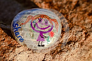 Painted rock with girl holding flower and word share