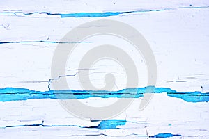 Painted rough wooden background, old wall with cracked paint white on blue backdrop.