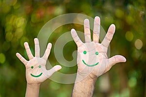 Painted smiley face on the palms against green background