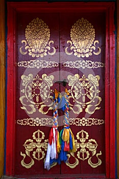 Painted with traditional buddhist symbols red door with laced hadags sacred scarves as handles in Tovkhon Monastery, Mongolia