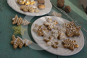 Painted traditional Christmas gingerbreads arranged on white plates on old vintage painted table, various xmas shapes