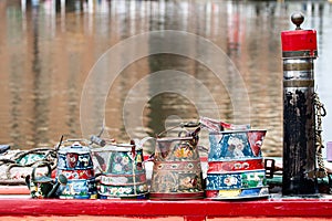 Painted watering canisters on a red wooden board