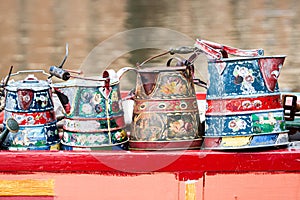 Painted watering canisters on a red wooden board