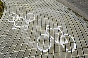 Painted white bike icons on gray bike lane pavement bricks, bicycle signs on bicycle lane