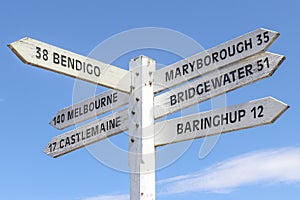 Painted wooden signpost at Maldon town centre showing distance and directions to surrounding towns in a blue sky