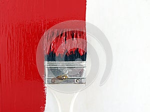 paint brush painting bright red color on white wooden wall