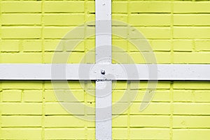 Painted yellow brick wall texture, metal white quadrangular frame, crossbeams, urban background, space for text