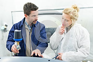 painter with airgun explaining technique to spray car