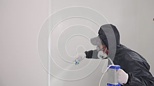 Painter builder man in protective gear works. Paints the wall with an airless spray. Finisher worker