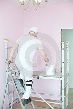 Painter climbs a ladder on scaffolding for