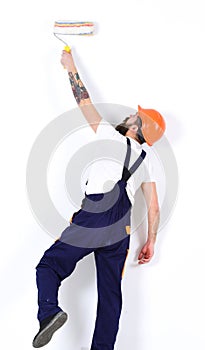 Painter, decorator, construction worker works in front of white wall, holds paint roller, white background. Man in