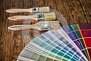 Painter and decorator work table with house project, color swatches, painting roller and paint brushes