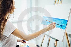 Painter girl drawing sea-scape on canvas in her workshop. Concept of fine-art classes