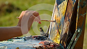 Painter hand drawing oil paints outdoor. Unknown artist painting canvas closeup