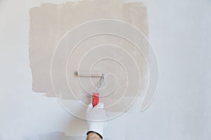 Painter hand in white glove painting a wall with paint roller