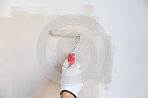 Painter hand in white glove painting a wall with paint roller