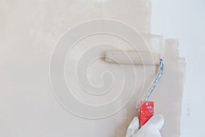 Painter hand in white glove painting a wall with paint roller