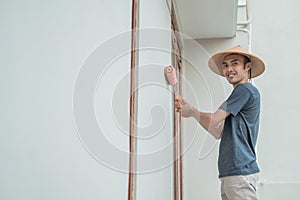 A painter with a hat is painting using a paint roller