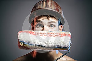 Painter man. Closeup portrait of painter, designer or builder with paint roller. Professional painter in hard hat with