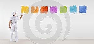 Painter man with paint brush painting color samples isolated