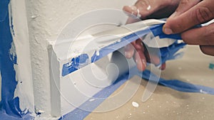 Painter Man Removing masking blue tape from molding, baseboard