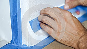 Painter Man Using Masking Blue Tape to Secure Baseboard, Moulding